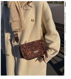 Detail of leopard print crossbody bag featuring metal logo and wide textile shoulder strap