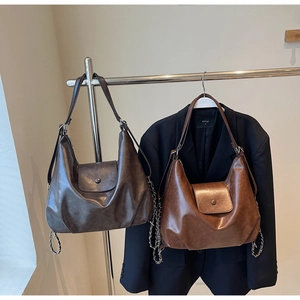 Detail of vintage tote bag featuring a leather strap with metal chain and foldover flap