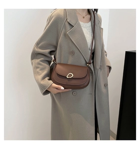 Detail of vintage brown saddle bag featuring a unique gold cutout buckle and matte leather