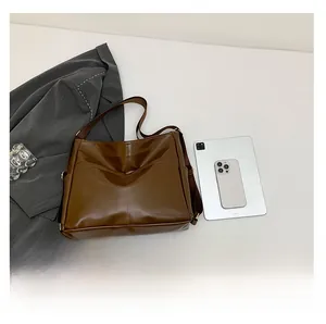 Flat lay of brown leather tote bag with V-shaped stitching alongside professional office attire