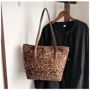 Detail of leopard print tote bag featuring brown leather handles and reinforced stitching