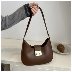Detail of dark brown leather crescent bag with golden metal push-lock and adjustable strap