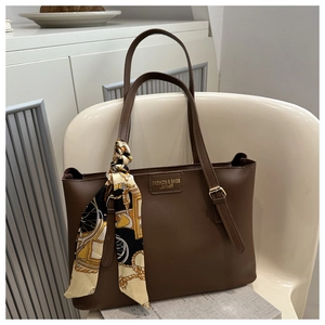 Détail d'un sac cabas en cuir marron foncé orné d'un foulard en soie au motif carrosse