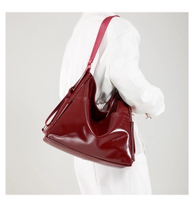 Detail of burgundy glossy faux leather tote bag with metallic hardware and adjustable strap
