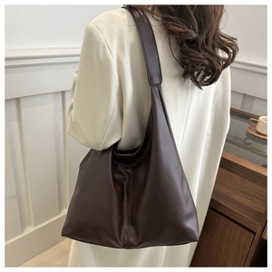 Detail of a large coffee brown leather tote bag worn with a stylish white coat