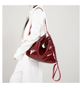 Detail of dark red glossy shoulder bag featuring adjustable straps and soft texture