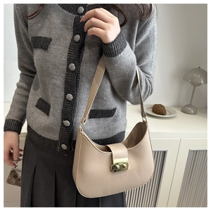 Detail of a beige leather saddle bag with gold metal buckle shown in a lifestyle setting
