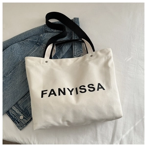 Close-up of canvas tote bag with FANYISSA lettering and black adjustable strap