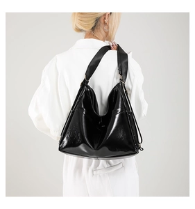 Detail showing high-gloss black patent leather texture and wide nylon strap on tote bag