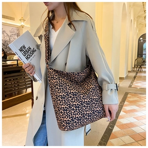 Fashionable leopard print large hobo bag with wide shoulder strap on model in urban street