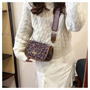 Close-up of leopard print crossbody bag with wide patterned strap and metal plaque