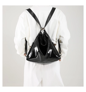 Detail of glossy black faux leather tote with triangular structure and nylon strap