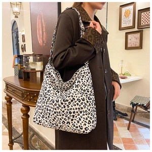 Detail view of large leopard print tote bag styled with a brown coat in a cozy setting