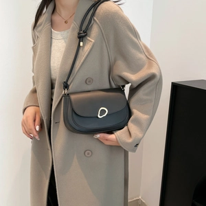 Minimalist black semi-circle saddle bag with gold ring buckle and decorative knotted strap