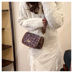 Close-up of leopard print crossbody bag with fashion tag and textured wide shoulder strap