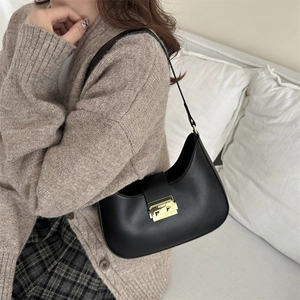 Retro black faux leather crescent hobo bag with gold buckle on a sofa setting
