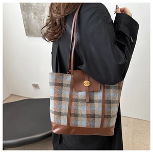 Detail of retro plaid tote bag with brown leather trim and metallic 'N' clasp buckle