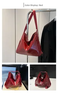 Detail view of large red glossy hobo bag with wide fabric strap and side pockets