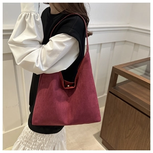 Detailed close-up of burgundy suede tote bag showing magnetic snap closure and texture