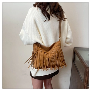 Close-up of brown suede tote bag featuring long decorative tassels and adjustable strap