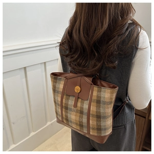 Detail of vintage plaid wool backpack showing the classic check pattern and leather trim