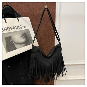 Detailed view of black suede tote bag with dense fringe tassels and top zipper closure