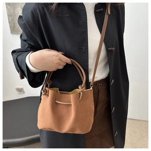 Close-up of brown suede bucket bag with soft pleated design and yellow lining detail