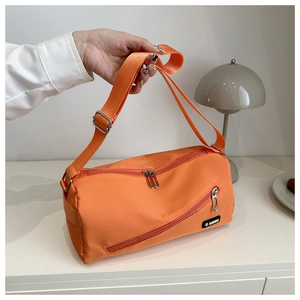 Détail d'un sac bandoulière en nylon orange vif avec poche zippée et logo tendance