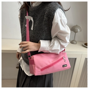 Détail d'un sac bandoulière en nylon rose avec large sangle porté par un modèle