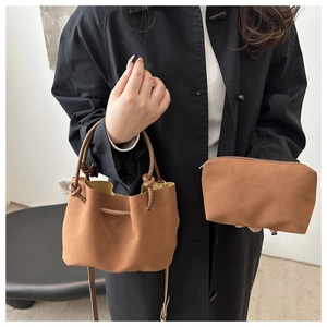 Detail of vintage brown suede bucket bag with matching clutch and knot handle detail