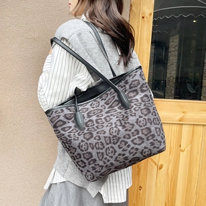 Vintage leopard print tote bag with black straps worn by a model in a casual setting