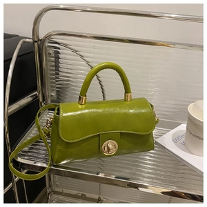 Detail of lime green faux leather handbag featuring a gold circular twist lock and handle