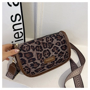 Detail of leopard print cylinder bag with wide geometric strap and golden hooks