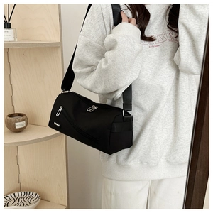 Détail du sac bandoulière en nylon noir avec compartiments zippés porté par le modèle