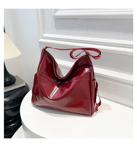 Detailed close-up of burgundy glossy faux leather tote bag with functional side pockets