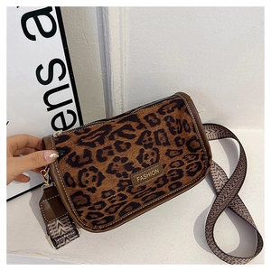 Detail of leopard print handbag featuring a gold FASHION metal plate and wide textile strap