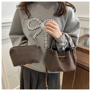 Detail of dark brown vintage pleated bucket bag and pouch set held by a model