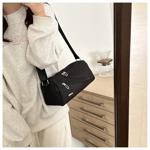 Détail d'un sac polochon en nylon noir avec étiquette jaune et fermetures éclair en métal