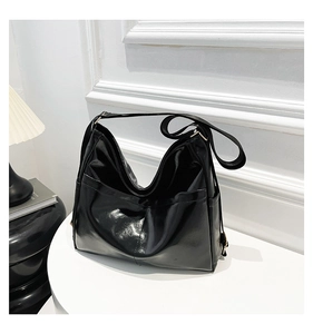 Close-up of shiny black leather hobo bag with adjustable strap and large front pocket