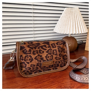 Close-up of leopard print crossbody bag featuring a fashion patch and wide woven strap