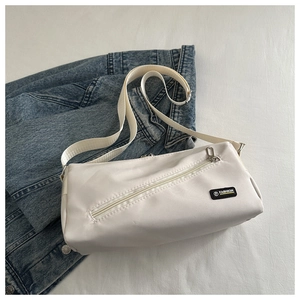 Détail du sac bandoulière en nylon blanc cassé avec fermeture éclair et étiquette mode