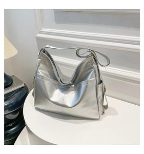 Detail of silver metallic tote bag with side pocket on a white minimalist display stand