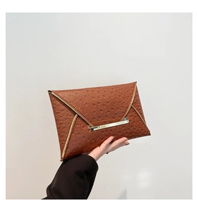 Detail of dark brown ostrich texture envelope clutch with gold metal trim and flap