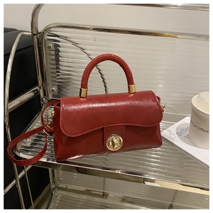 Detail view of deep red oil-wax leather handbag with vintage gold twist lock buckle