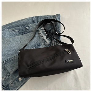 Détail du sac bandoulière en nylon noir avec étiquette mode et poche à fermeture