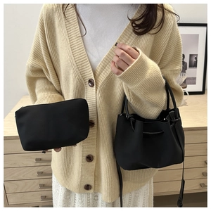 Detail of a black pleated bucket bag and matching rectangular clutch in a 2-piece set