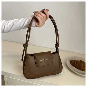Detailed view of dark brown leather handbag with white text logo and knot strap detail