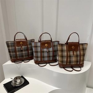 Three plaid tweed backpacks with leather trim and N buckle on white display stands