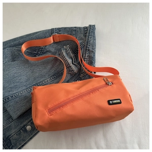 Détail de la sacoche en nylon orange avec poche zippée et logo tendance sur veste denim