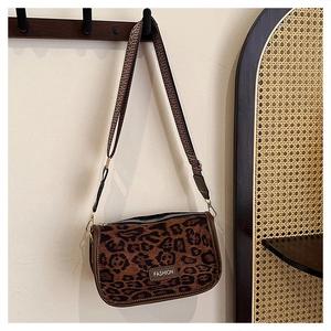 Detailed view of leopard print crossbody bag with wide strap and fashion emblem
